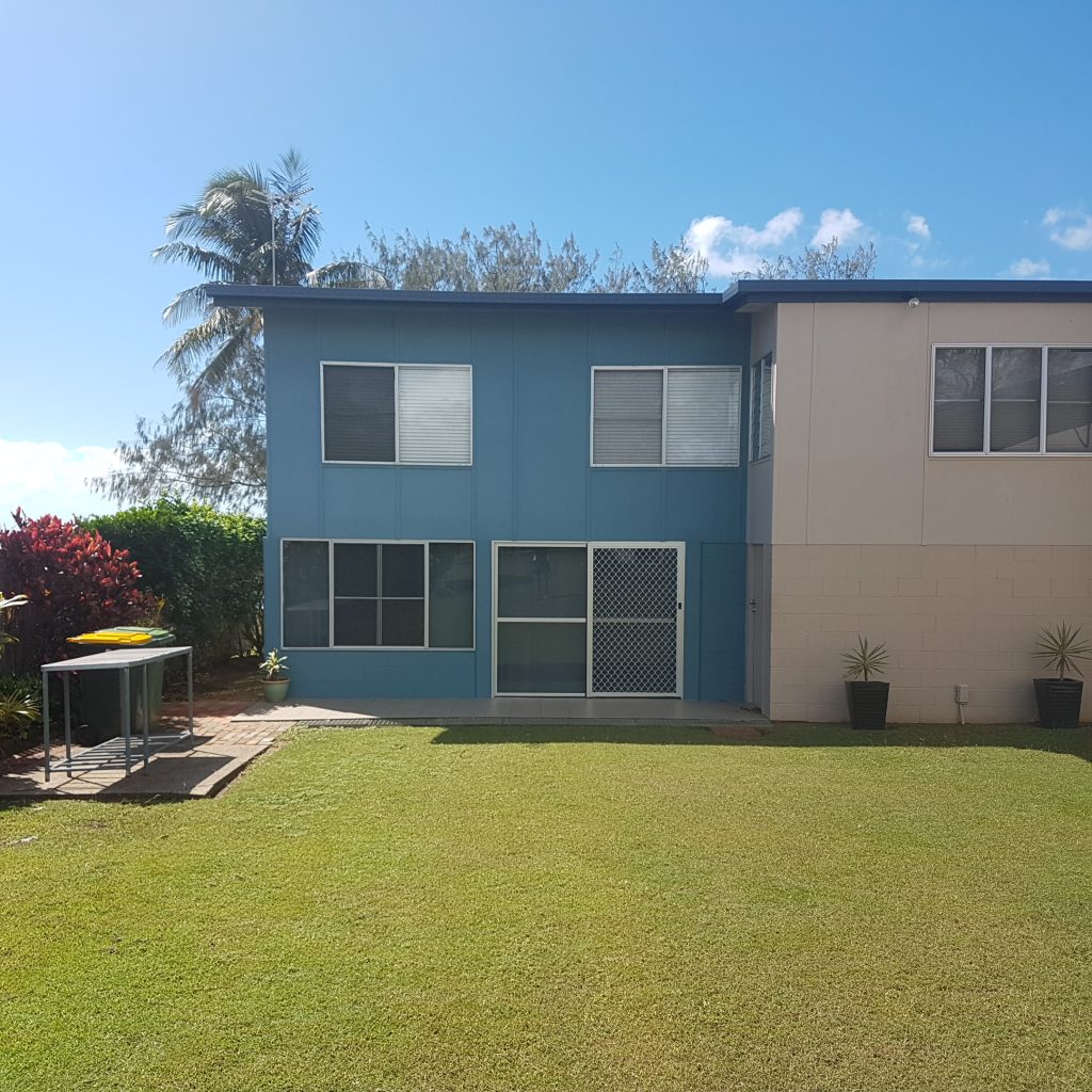 Two-storey blue and cream home with a lawn backyard