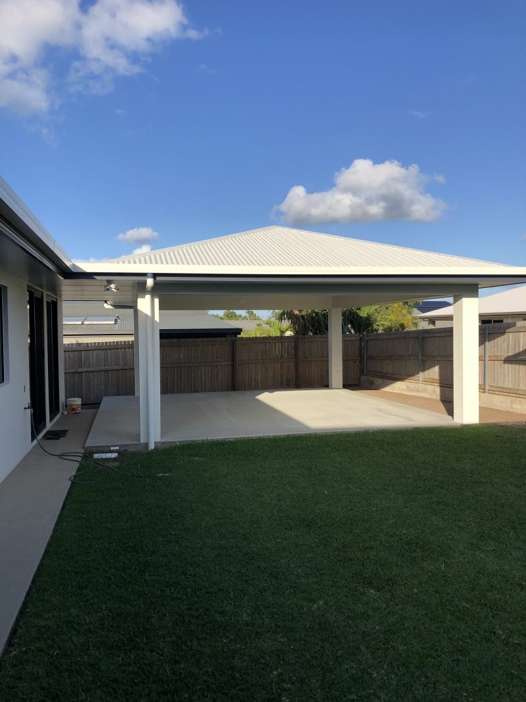 Hip-roofed patio with white posts over a concrete slab beside a lawn