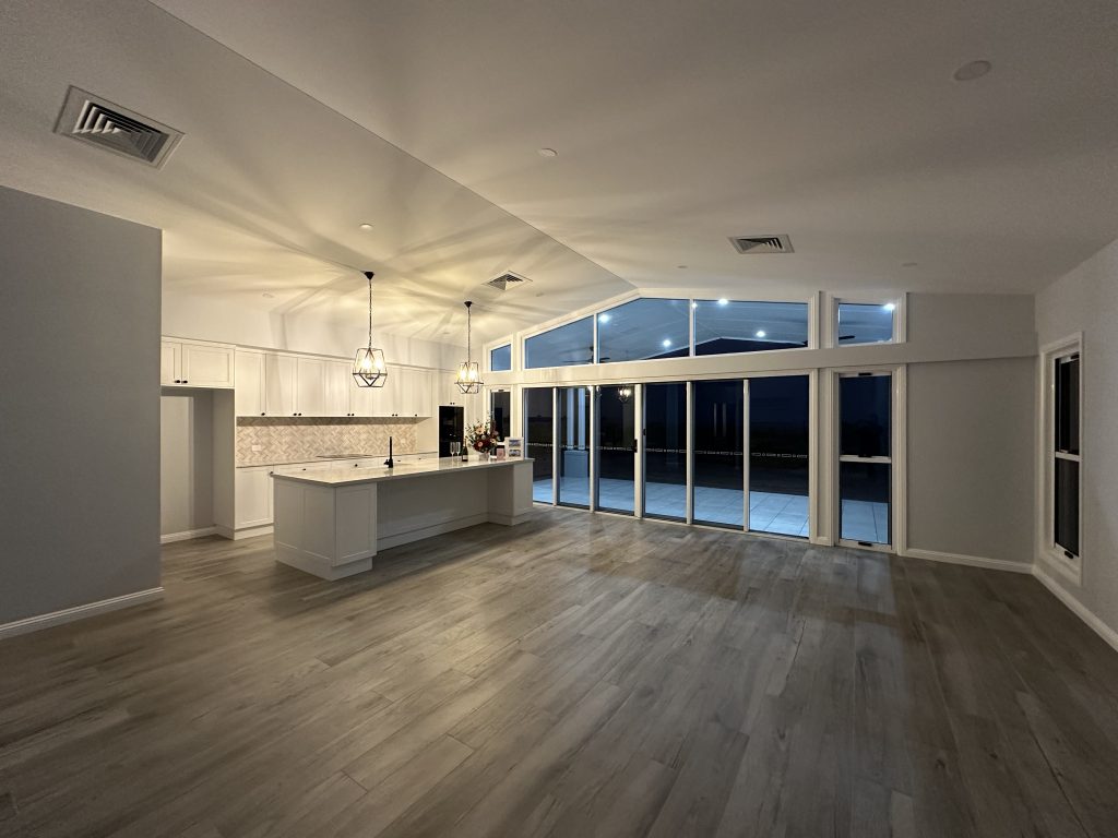Open-plan living area with timber-look floors, kitchen island and pendant lights