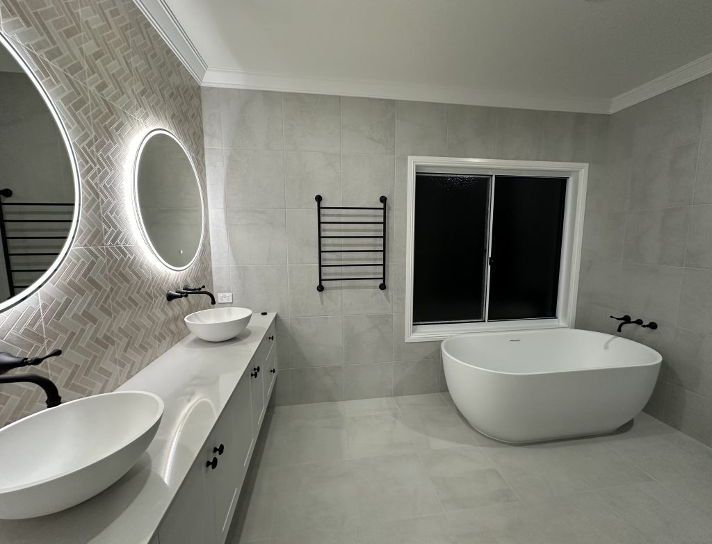 Bathroom with a freestanding bath, double basins and round backlit mirrors