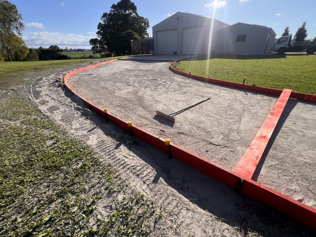 Formwork set out for a curved concrete driveway leading to a large shed