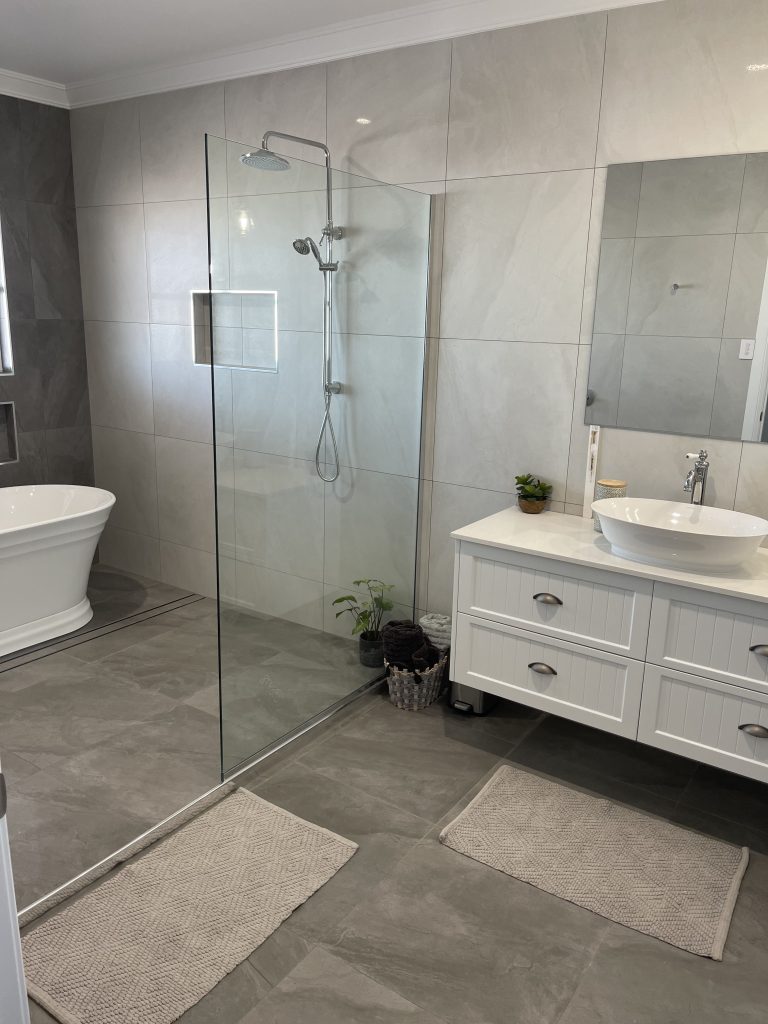 Bathroom with a walk-in glass shower, freestanding bath and white vanity