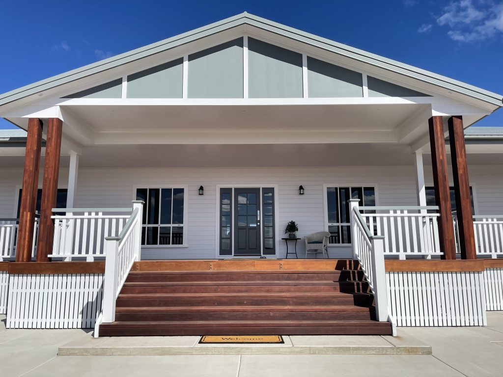 White weatherboard home with a front verandah, timber posts and wide timber steps