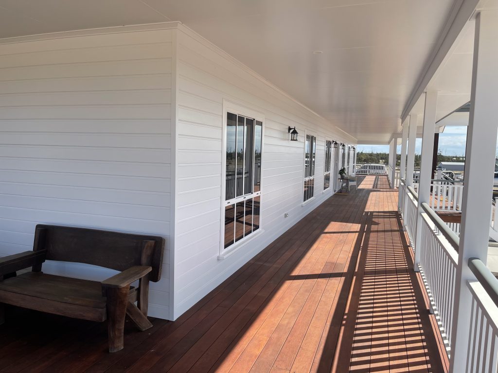 Long timber verandah deck with white balustrade along a weatherboard home