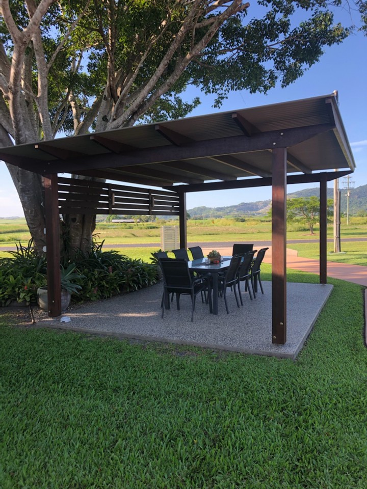 Dark timber pergola over a concrete patio with an outdoor dining setting